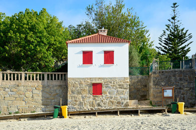 Modelo de fachada de casa blanca marinera pequeña de dos plantas con revestimiento de piedra, tejado a dos aguas y tejado de teja de barro