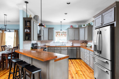 Enclosed kitchen - mid-sized transitional u-shaped medium tone wood floor and brown floor enclosed kitchen idea in Charleston with gray cabinets, wood countertops, white backsplash, stainless steel appliances, no island, a double-bowl sink and brown countertops