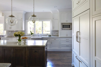 Design ideas for a transitional kitchen in Chicago with a farmhouse sink, beaded inset cabinets, white cabinets, quartz benchtops, white splashback, stone tile splashback, panelled appliances, dark hardwood floors and with island.