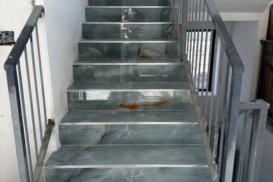 Ejemplo de escalera en U moderna de tamaño medio con escalones con baldosas, contrahuellas con baldosas y/o azulejos y barandilla de metal