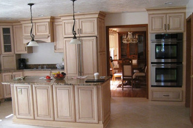 This is an example of a large mediterranean kitchen in Other with light wood cabinets, granite benchtops, stainless steel appliances, with island, an undermount sink, raised-panel cabinets and porcelain floors.
