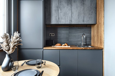 Design ideas for a small contemporary galley open plan kitchen in Moscow with a drop-in sink, grey cabinets, grey splashback, porcelain splashback, black appliances, laminate floors, brown floor and brown benchtop.