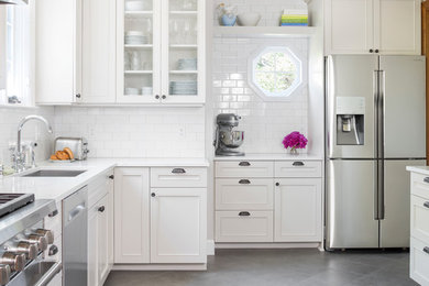 Mid-sized traditional l-shaped kitchen in Seattle with an undermount sink, white cabinets, quartz benchtops, white splashback, subway tile splashback, stainless steel appliances, porcelain floors and beaded inset cabinets.