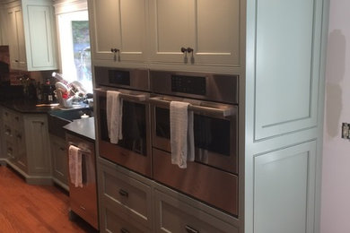 Eat-in kitchen - large transitional l-shaped medium tone wood floor eat-in kitchen idea in Other with a farmhouse sink, beaded inset cabinets, green cabinets, soapstone countertops, stainless steel appliances and an island