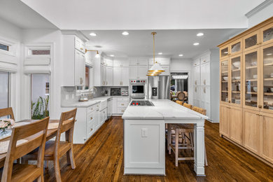 アトランタにある高級な中くらいなトランジショナルスタイルのおしゃれなキッチン (エプロンフロントシンク、シェーカースタイル扉のキャビネット、白いキャビネット、珪岩カウンター、白いキッチンパネル、クオーツストーンのキッチンパネル、シルバーの調理設備、濃色無垢フローリング、茶色い床、白いキッチンカウンター) の写真