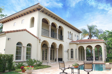 Large tuscan yellow two-story stucco exterior home photo in Orlando