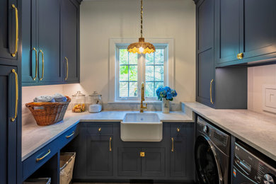Mid-sized beach style u-shaped slate floor and gray floor dedicated laundry room photo in New York with a farmhouse sink, recessed-panel cabinets, blue cabinets, granite countertops, white walls, a side-by-side washer/dryer and beige countertops