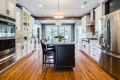 Example of a large classic galley medium tone wood floor and brown floor eat-in kitchen design in Miami with recessed-panel cabinets, white cabinets, granite countertops, an island, gray countertops, a double-bowl sink, beige backsplash, stone tile backsplash and stainless steel appliances