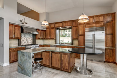 This is an example of a large transitional l-shaped eat-in kitchen in San Diego with an undermount sink, recessed-panel cabinets, medium wood cabinets, granite benchtops, beige splashback, ceramic splashback, stainless steel appliances, porcelain floors and with island.