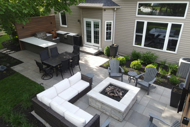 Example of a large trendy backyard stone patio design in Chicago with a fire pit and no cover