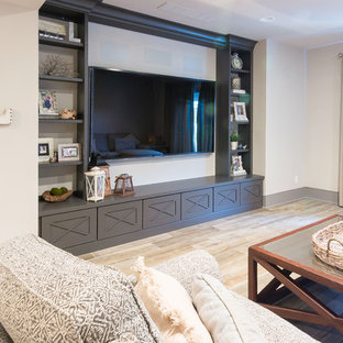 Exemple d'une très grande salle de cinéma nature ouverte avec un mur beige, sol en stratifié, un téléviseur fixé au mur et un sol beige.