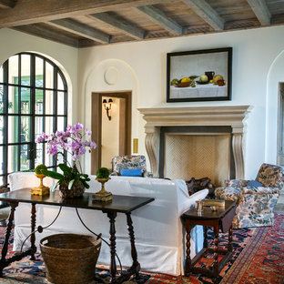 Esempio di un soggiorno mediterraneo di medie dimensioni e aperto con sala formale, pareti bianche, pavimento in cemento, camino classico, cornice del camino in legno, nessuna TV e pavimento grigio