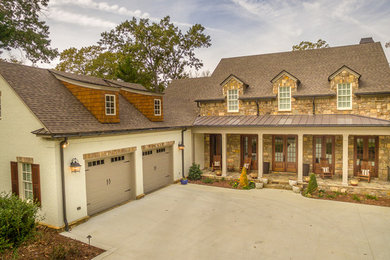 Example of a large classic beige three-story stone gable roof design
