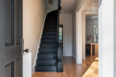 Staircase - painted straight wood railing staircase idea in New York with painted risers