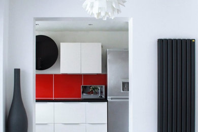 Mid-sized contemporary l-shaped separate kitchen in Buckinghamshire with a single-bowl sink, flat-panel cabinets, white cabinets, laminate benchtops, red splashback, stainless steel appliances, porcelain floors and no island.