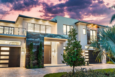 Large trendy white two-story stucco house exterior photo in Miami with a hip roof, a tile roof and a gray roof