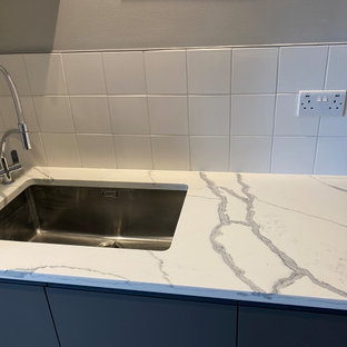 Idee per una grande lavanderia multiuso design con lavello da incasso, ante lisce, ante grigie, top in quarzite, paraspruzzi bianco, paraspruzzi in gres porcellanato, pareti beige, pavimento in laminato, lavatrice e asciugatrice affiancate, pavimento grigio e top multicolore