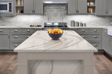 Inspiration for a transitional dark wood floor kitchen remodel in Minneapolis with a farmhouse sink, shaker cabinets, gray cabinets, quartzite countertops, gray backsplash, ceramic backsplash and an island