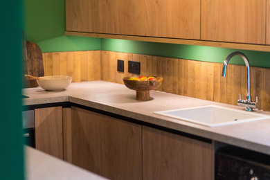 This is an example of a small midcentury galley enclosed kitchen in London with a built-in sink, flat-panel cabinets, medium wood cabinets, composite countertops, brown splashback, porcelain splashback, stainless steel appliances, terracotta flooring, grey floors and grey worktops.