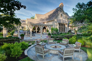 Example of a large transitional backyard stone patio design in Chicago with a fire pit and a pergola