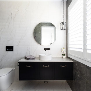 This is an example of a mid-sized beach style 3/4 bathroom in Sydney with recessed-panel cabinets, black cabinets, a curbless shower, a wall-mount toilet, white tile, ceramic tile, white walls, a drop-in sink, granite benchtops, a hinged shower door, white benchtops, a single vanity and a floating vanity.