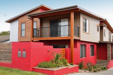 This is an example of a large modern two-storey red duplex exterior in Other with concrete fiberboard siding.