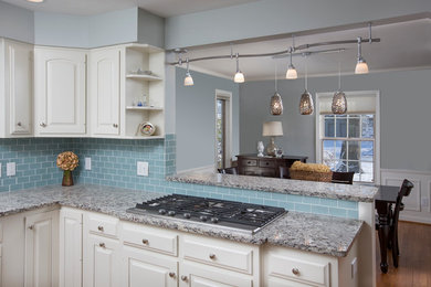 Example of a mid-sized transitional l-shaped medium tone wood floor enclosed kitchen design in Columbus with granite countertops, raised-panel cabinets, white cabinets, blue backsplash, ceramic backsplash and stainless steel appliances