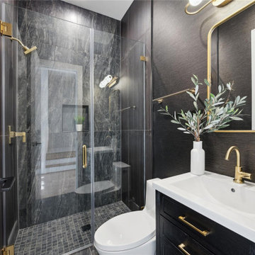 Dramatic powder bath with black marble walls and brass fixtures