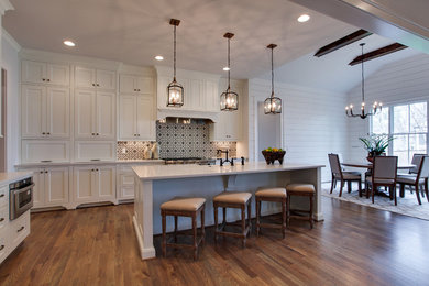 Country medium tone wood floor kitchen photo in Nashville with shaker cabinets, white cabinets, quartz countertops, white backsplash, cement tile backsplash, stainless steel appliances and an island