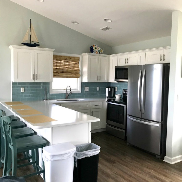 Mid-sized beach style u-shaped dark wood floor and brown floor eat-in kitchen photo with an undermount sink, shaker cabinets, white cabinets, blue backsplash, subway tile backsplash, stainless steel a