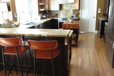 Inspiration for a mid-sized contemporary u-shaped light wood floor enclosed kitchen remodel in Portland Maine with a farmhouse sink, shaker cabinets, dark wood cabinets, quartzite countertops, multicolored backsplash, stone slab backsplash, stainless steel appliances and an island