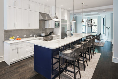 Design ideas for a transitional galley eat-in kitchen in DC Metro with a farmhouse sink, shaker cabinets, white cabinets, grey splashback, subway tile splashback, stainless steel appliances, dark hardwood floors, with island, brown floor and white benchtop.
