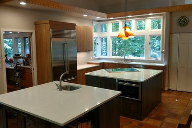 Kitchen - large modern terra-cotta tile and brown floor kitchen idea in Other with an undermount sink, medium tone wood cabinets, quartz countertops, beige backsplash, porcelain backsplash, stainless steel appliances and two islands