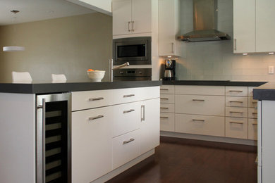 Open concept kitchen - mid-sized modern l-shaped medium tone wood floor open concept kitchen idea in Toronto with an undermount sink, flat-panel cabinets, white cabinets, quartz countertops, white backsplash, glass tile backsplash, stainless steel appliances and an island