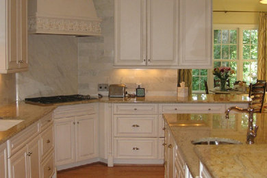 Inspiration for a large timeless l-shaped light wood floor eat-in kitchen remodel in Other with a farmhouse sink, white cabinets, white backsplash, stainless steel appliances, an island, raised-panel cabinets, granite countertops and marble backsplash