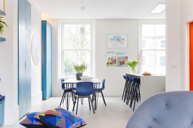 Large contemporary open plan dining room in London with white walls, light hardwood flooring and a wood burning stove.