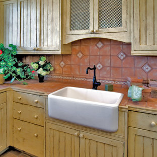 Idées déco pour une arrière-cuisine méditerranéenne en U de taille moyenne avec un évier de ferme, un placard à porte affleurante, des portes de placard jaunes, un plan de travail en marbre, une crédence multicolore, une crédence en carreau de terre cuite et un sol en carreau de terre cuite.