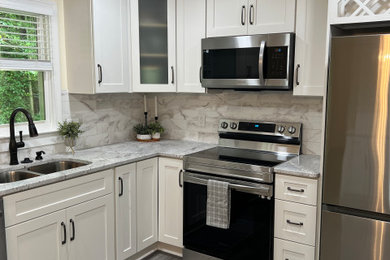 Example of a mid-sized trendy l-shaped laminate floor and gray floor eat-in kitchen design in Raleigh with a double-bowl sink, recessed-panel cabinets, white cabinets, granite countertops, white backsplash, ceramic backsplash, stainless steel appliances, a peninsula and white countertops