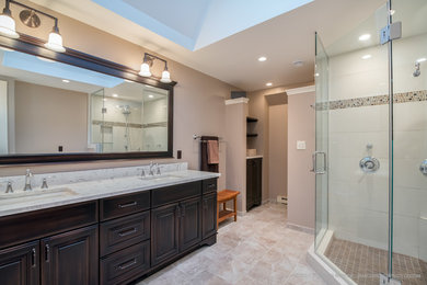 This is an example of an expansive classic ensuite bathroom in Milwaukee with freestanding cabinets, brown cabinets, a corner shower, white tiles, porcelain tiles, beige walls, porcelain flooring, a submerged sink, engineered stone worktops, beige floors, a hinged door and white worktops.