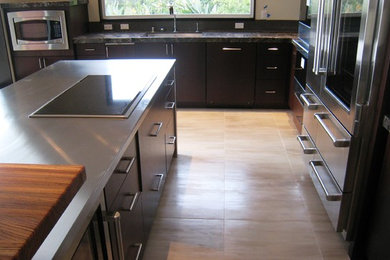 Mid-sized trendy u-shaped kitchen photo in Hawaii with flat-panel cabinets, dark wood cabinets, granite countertops, stainless steel appliances and an island