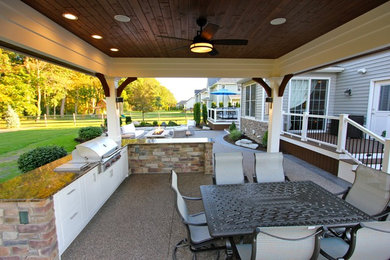Example of a mid-sized classic backyard stamped concrete patio kitchen design in Other with a roof extension