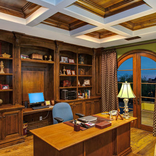 Idéer för stora vintage hemmabibliotek, med ett inbyggt skrivbord, gröna väggar och mellanmörkt trägolv