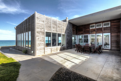Photo of a large beach style split-level brown exterior in Melbourne with wood siding and a flat roof.
