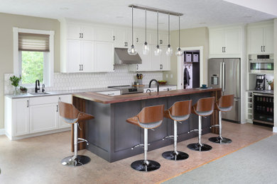 Inspiration for a large contemporary cork floor open concept kitchen remodel in Grand Rapids with a farmhouse sink, shaker cabinets, white cabinets, quartz countertops, white backsplash, ceramic backsplash, stainless steel appliances, an island and gray countertops
