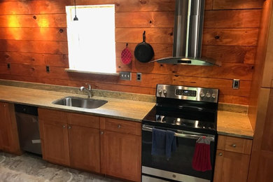Example of an arts and crafts single-wall kitchen design in Other with a single-bowl sink, shaker cabinets, medium tone wood cabinets, granite countertops, wood backsplash, stainless steel appliances and gray countertops