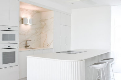 На фото: кухня в стиле модернизм с белыми фасадами и белой столешницей