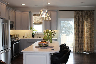 Mid-sized transitional l-shaped medium tone wood floor and brown floor kitchen photo in Chicago with an undermount sink, recessed-panel cabinets, gray cabinets, stainless steel countertops, stainless steel appliances and an island