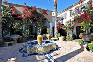 Large mediterranean courtyard partial sun garden in Phoenix with a water feature and natural stone pavers.