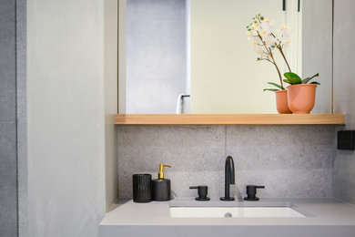 Photo of a mid-sized modern master bathroom in Melbourne with flat-panel cabinets, black cabinets, a corner shower, gray tile, stone tile, engineered quartz benchtops, a hinged shower door and grey benchtops.