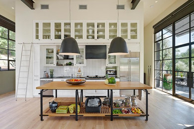 Inspiration for a small cottage single-wall light wood floor open concept kitchen remodel in San Francisco with an undermount sink, glass-front cabinets, white cabinets, white backsplash, subway tile backsplash, stainless steel appliances, an island and wood countertops